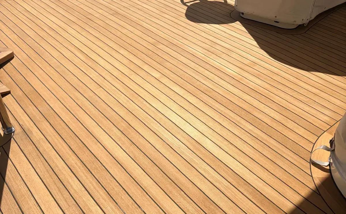 A newly finished teak deck with dark seams curving around exterior seating
