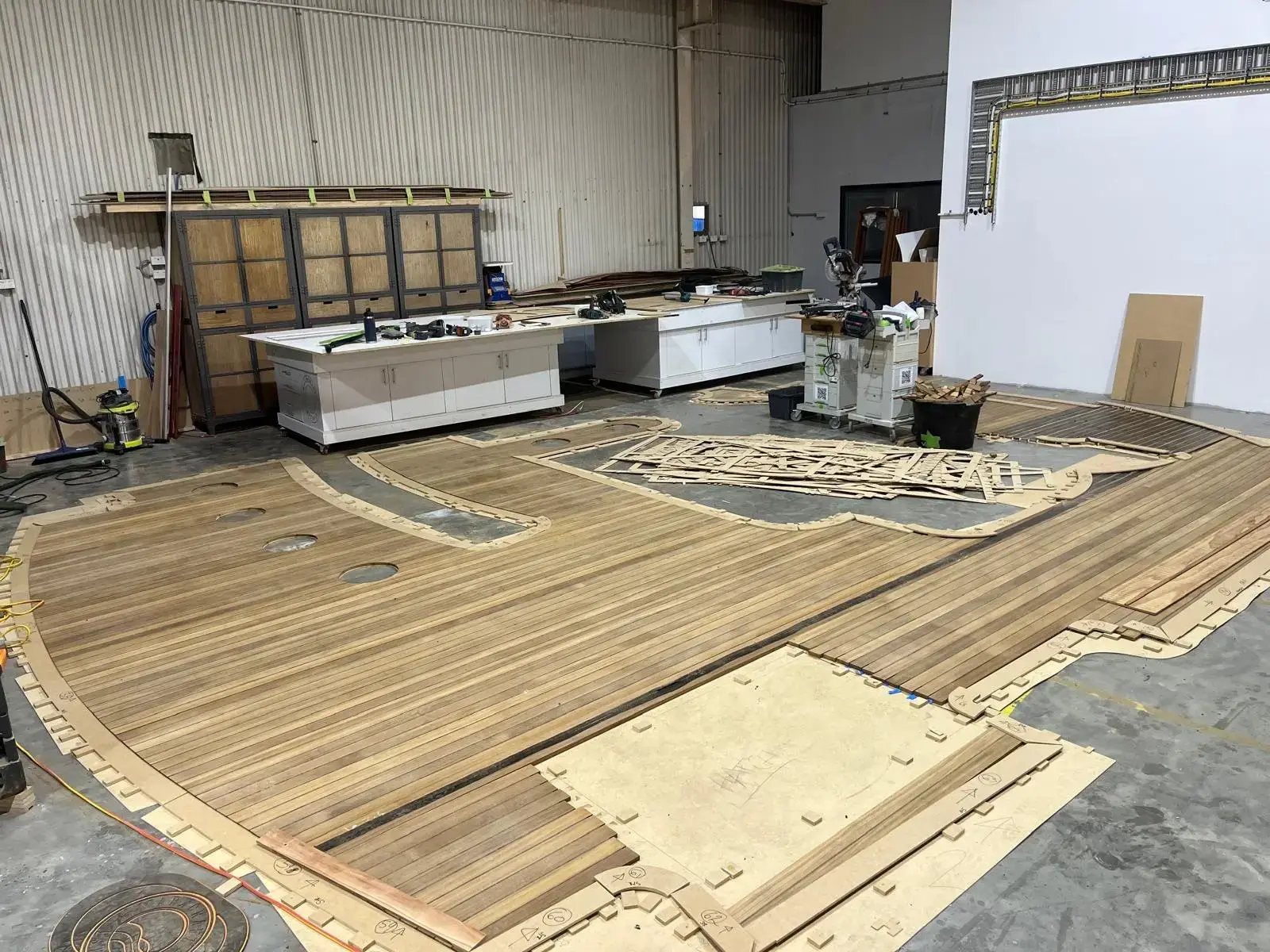 Teak deck panels and templates laid out on the workshop floor