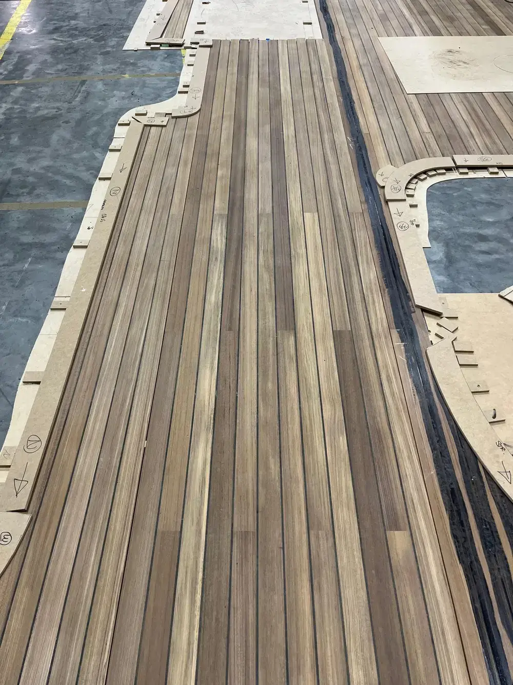 Teak planks and margin boards laid out on templates on the workshop floor